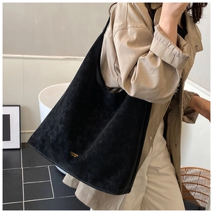 Detail of black faux suede tote bag on model showing large capacity and soft texture