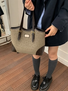 Leopard print canvas tote bag with leather straps and metal logo plate shown on model