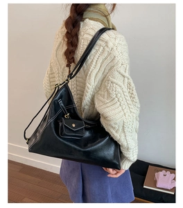 Detail of black triangular hobo bag with contrast white stitching and mini coin purse pouch