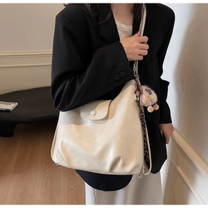 Dettaglio della borsa tote in pelle PU crema con fibbia rotonda e ciondolo di peluche