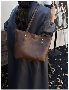 Detail of vintage brown tote bag with gold lettering logo and metal rivet reinforcement