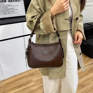 Detailed view of silver kangaroo logo on dark brown leather shoulder bag surface