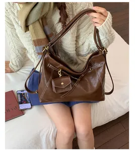 Dettaglio della borsa tote in pelle marrone con cuciture a contrasto e mini pochette inclusa