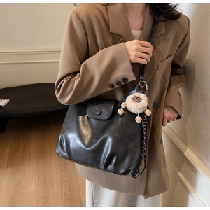 Dettaglio borsa tote in pelle PU nera con consistenza morbida e ciondolo agnello in peluche