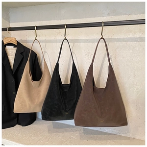 Trois sacs hobo minimalistes en daim beige noir et marron suspendus à des crochets