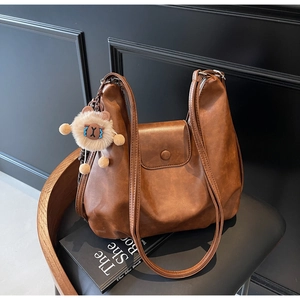 Dettaglio borsa tote marrone in pelle sintetica con texture opaca e ciondolo a leone