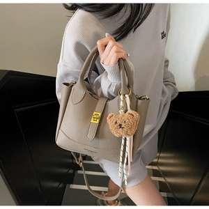 Détail du sac seau en cuir grainé avec fermoir doré et breloque ours en peluche