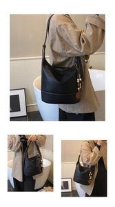 Detail der großen schwarzen Hobo-Tasche mit weißen Kontrastnähten und Holzperlen-Anhänger