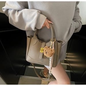 Détail du sac seau en cuir litchi kaki avec fermoir doré et pendentif ourson mignon