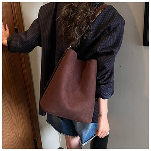 Close-up of dark brown suede bucket bag with stylish woven shoulder strap detail