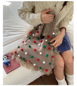 Detailed texture of brown knit tote bag with colorful pom-poms and long tassels