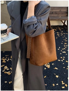 Outdoor shot showing brown suede shoulder bag with woven stitch details on a model