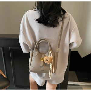 Détail du sac seau taupe avec fermoir doré, breloque ours en peluche et foulard rayé