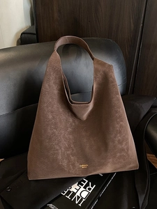 Retro dark brown large capacity tote bag in vintage leather on a stylish chair