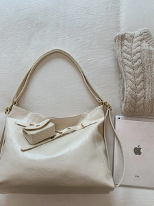Grande borsa tote in pelle beige con mini pochette e dettagli dorati accanto al tablet