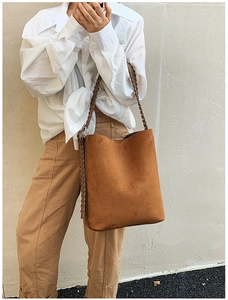 Close-up of brown suede bucket bag featuring elegant woven dual shoulder straps