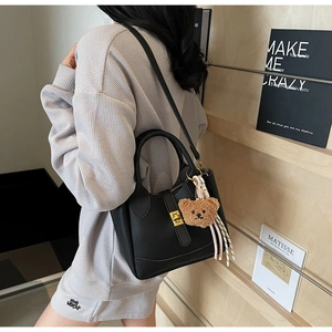 Détail du sac seau en cuir noir avec fermoir doré et pendentif ours en peluche