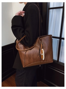 Detail of dark brown woven texture tote bag with colorful ethnic tassel and gold logo
