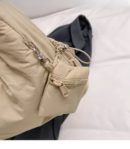 Detail of beige puffer tote bag featuring a detachable mini zipper pouch and metal hook