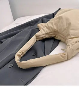 Detail of padded shoulder strap and smooth zipper on the beige quilted puffer hobo bag