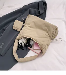 Flat lay of beige padded tote bag on a grey blazer showing spacious interior and mini pouch