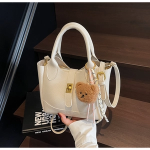 Détail du sac seau en cuir litchi blanc avec fermoir doré et breloque ours en peluche