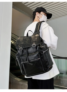 Close-up of black PU leather backpack with vintage buckles and functional zipper pockets
