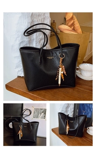 Detail of black woven tote bag with fringe charm and fashion lettering on leather