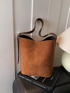 Brown suede bucket bag with woven handle and minimalist design for high-end lifestyle