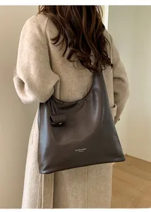 Détail du sac cabas en cuir marron foncé avec texture souple et petite pochette latérale