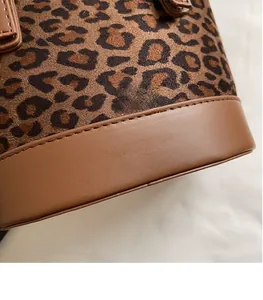 Détail du sac seau à imprimé léopard avec bordure en cuir marron et logo de marque