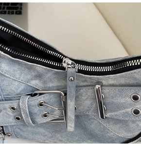 Détail d'un sac en jean bleu clair avec fermetures éclair argentées et boucle à œillets