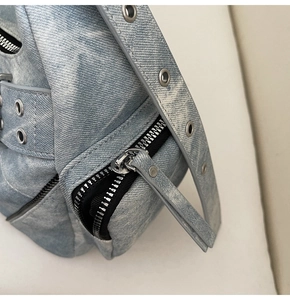 Gros plan du sac en denim bleu clair avec œillets métalliques et fermetures éclair noires