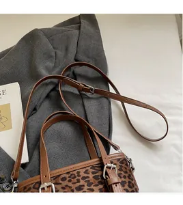 Détail de la bandoulière réglable du sac seau léopard sur une veste de costume grise