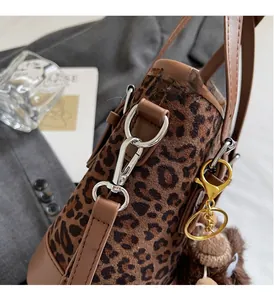 Détail du sac seau léopard avec garniture en cuir marron et pendentif ours doré