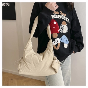 Detail of beige quilted puffer bag featuring a side drawstring and small coin purse attachment