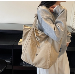 Detail of khaki casual tote bag with front pocket and branded metal logo on nylon fabric