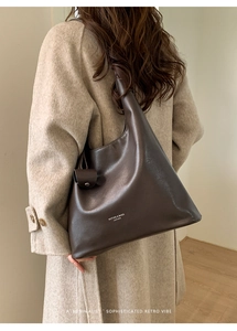 Détail d'un grand sac hobo en cuir marron foncé avec bandoulière large et pochette ronde