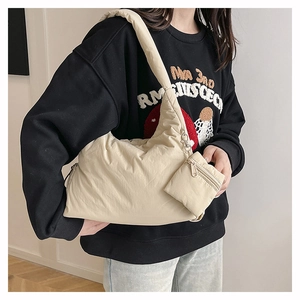Detail of beige quilted puffer bag featuring a matching mini zipper coin purse and wide strap