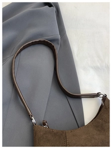 Detail of premium brown suede shoulder bag with durable leather strap and silver rings