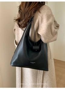 Detail of black pebbled leather tote bag with elegant drawstring and logo lettering