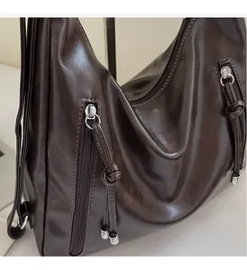 Detailed side view of dark brown leather tote bag showing silver metal hardware and zippers