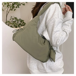 Detail of sage green quilted padded shoulder bag with drawstring and zip closure
