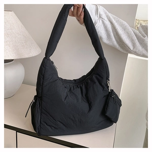Detail of black quilted padded shoulder bag with matching mini pouch and wide strap