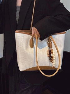 Chic two-tone herringbone tote bag with brown leather handles and colorful beaded charm