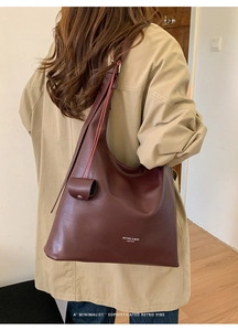 Detailed view of deep brown vintage leather tote with decorative mini pouch accessory