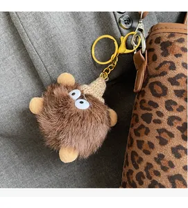 Détail d'un bijou de sac monstre en peluche avec grands yeux et porte-clés doré chic