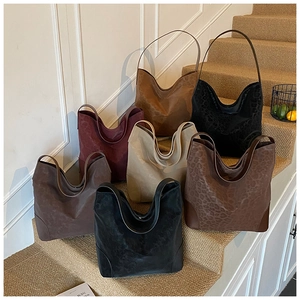 Collection of oversized leopard print and solid suede hobo bags on vintage stairs