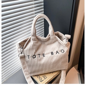 Detail of beige corduroy tote bag showing embroidered text and soft ribbed fabric texture