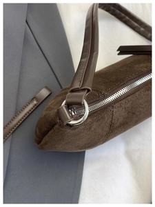 Detail shot of brown suede shoulder bag with silver zipper and smooth leather strap